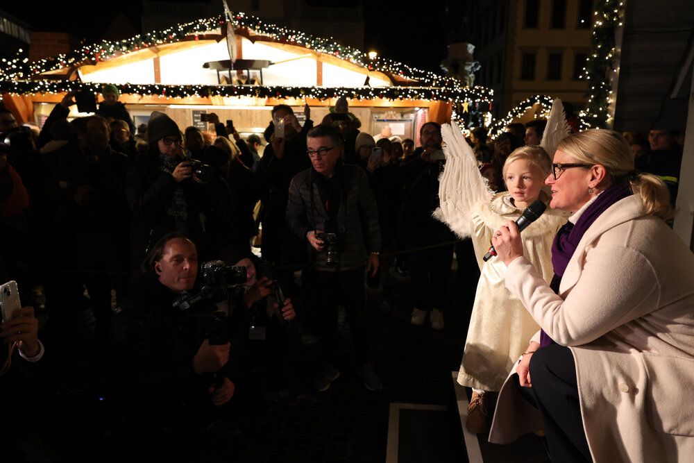 OB Eva Weber und der Weihnachtsengel sprechen in der noch dunklen Budengasse zu Schaulustigen