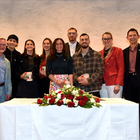 Gruppenbild vor Tisch, auf dem Blumen liegen