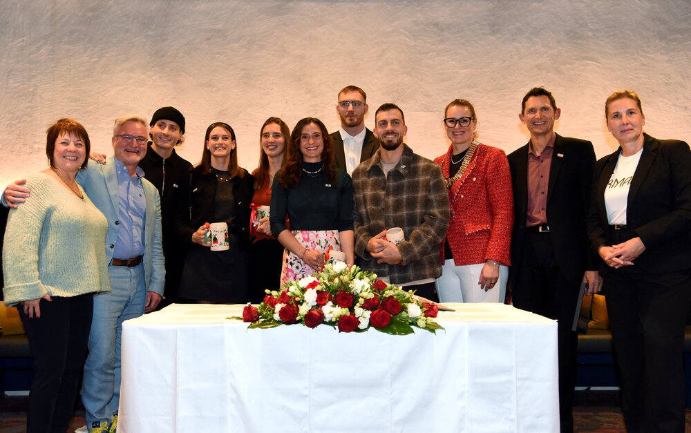 Gruppenbild vor Tisch, auf dem Blumen liegen