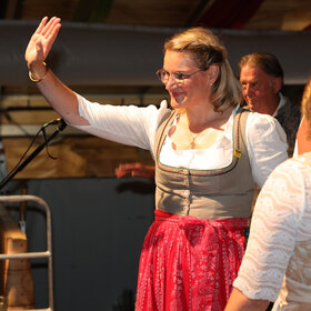 Frau im Dirndl winkt