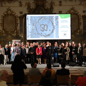 Gruppenbild vor grpoßer Leinwand, darauf "50 Jahre Integrationsbeirat"