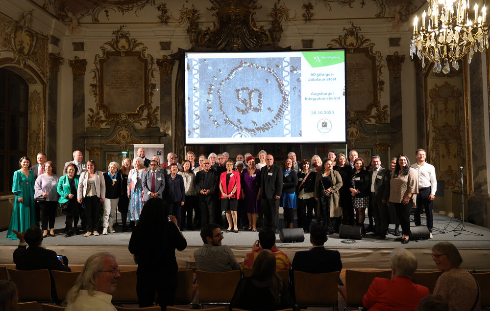 Gruppenbild vor grpoßer Leinwand, darauf "50 Jahre Integrationsbeirat"