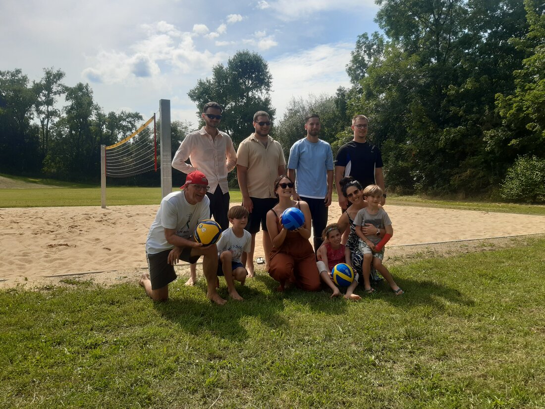 Eine Gruppe Jugendlicher mit zwei Mitarbeiterinnen aus der Stadtverwaltung und Umweltreferent Reiner Erben vor dem neuen Beachvolleyballfeld in der Firnhaberau.