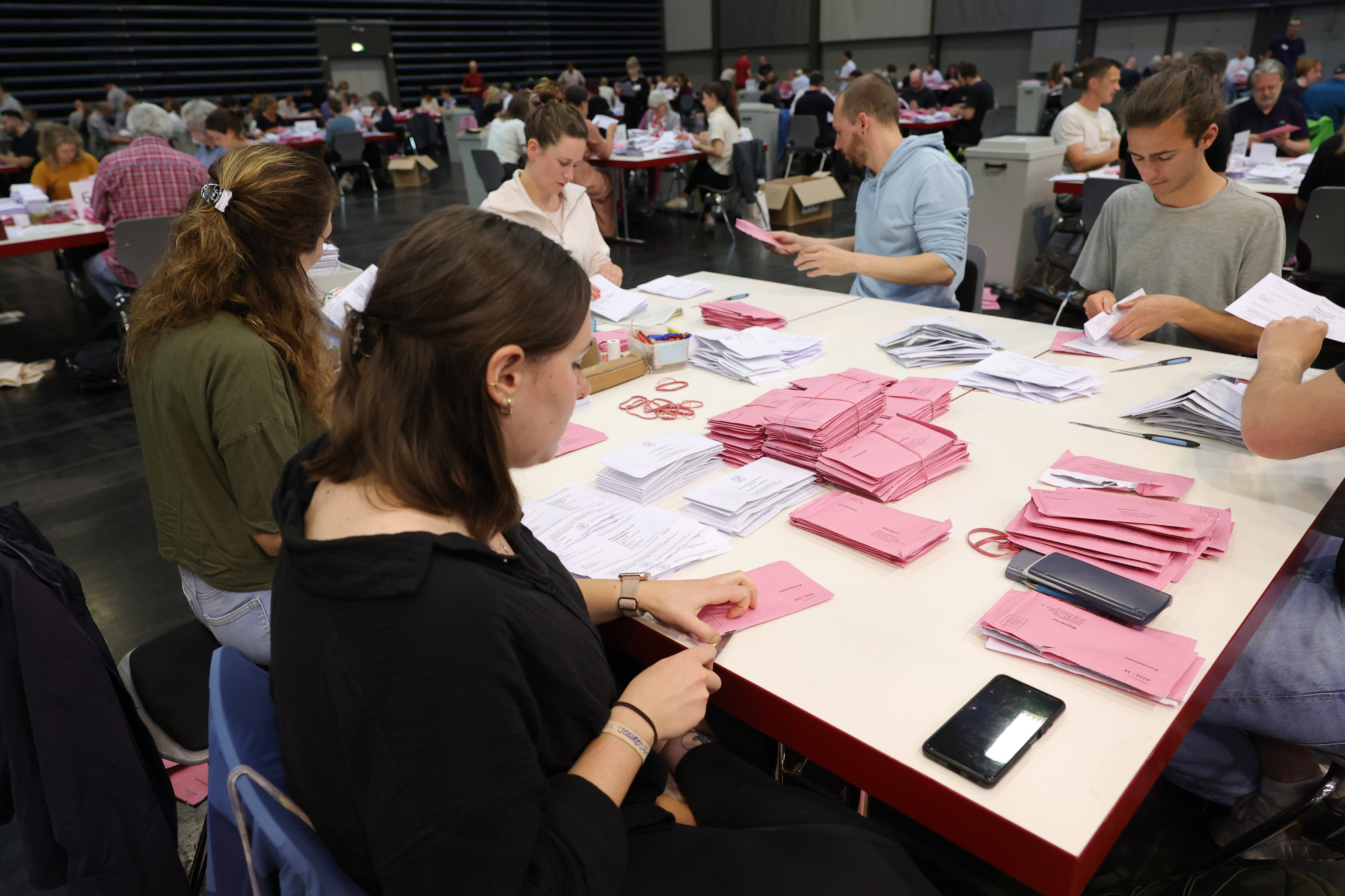 Viele Leute sitzen an großen Tischen und zählen Papierzettel