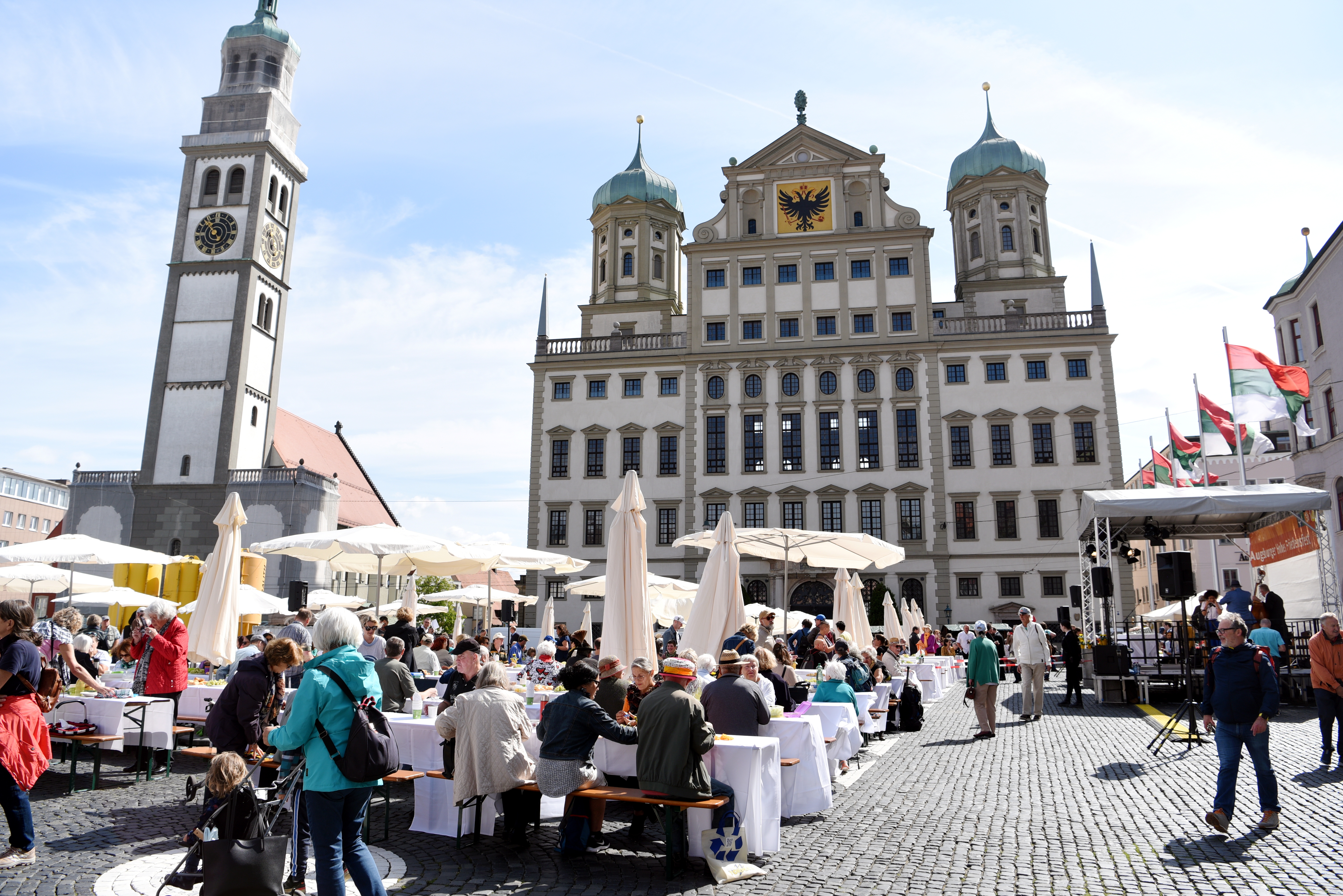 Viele Leute sitzen an Tischen auf dem Rathausplatz