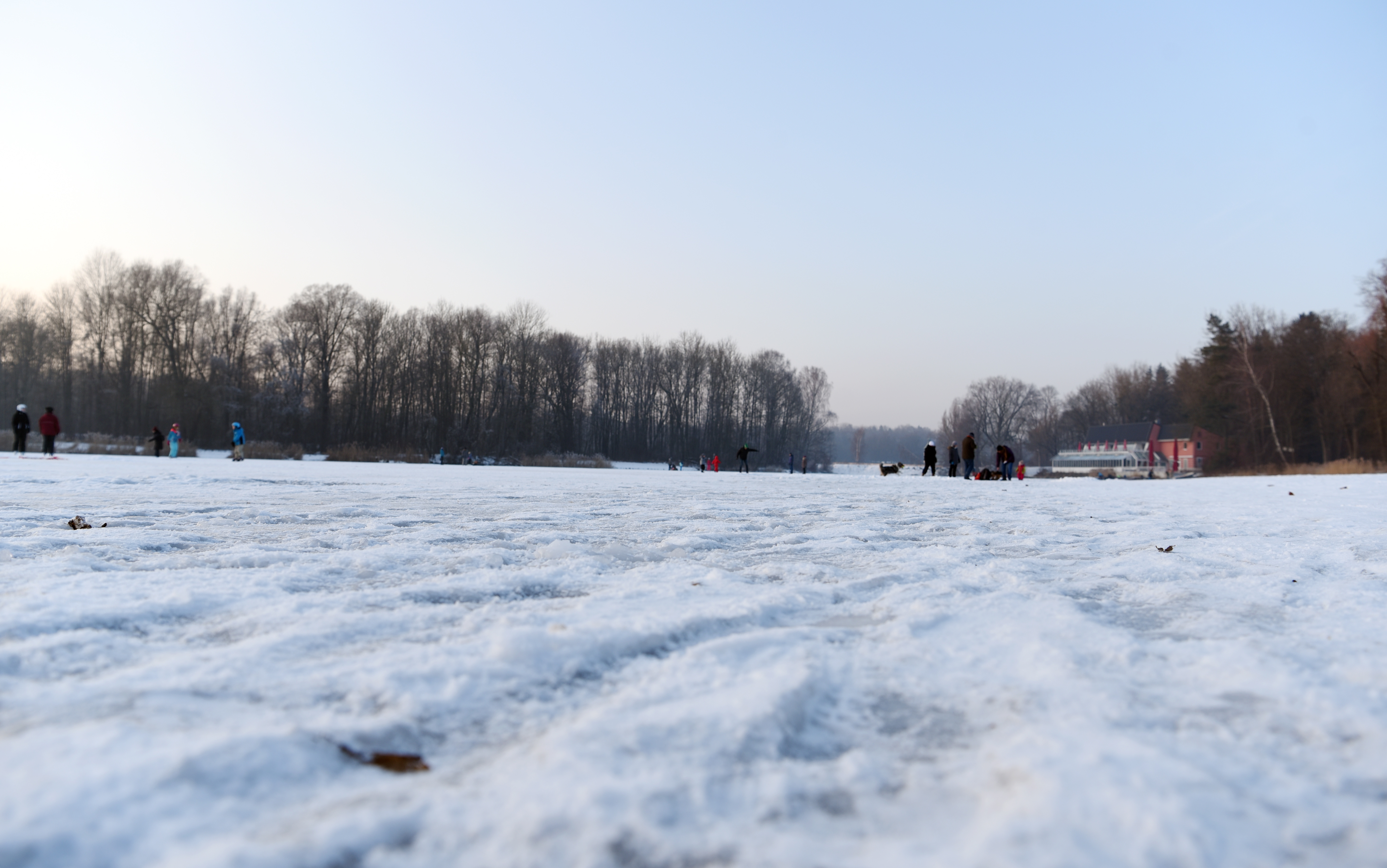 Ein zugefrorener See. Im Hintergrund sind Leute auf dem Eis zu erkennen.