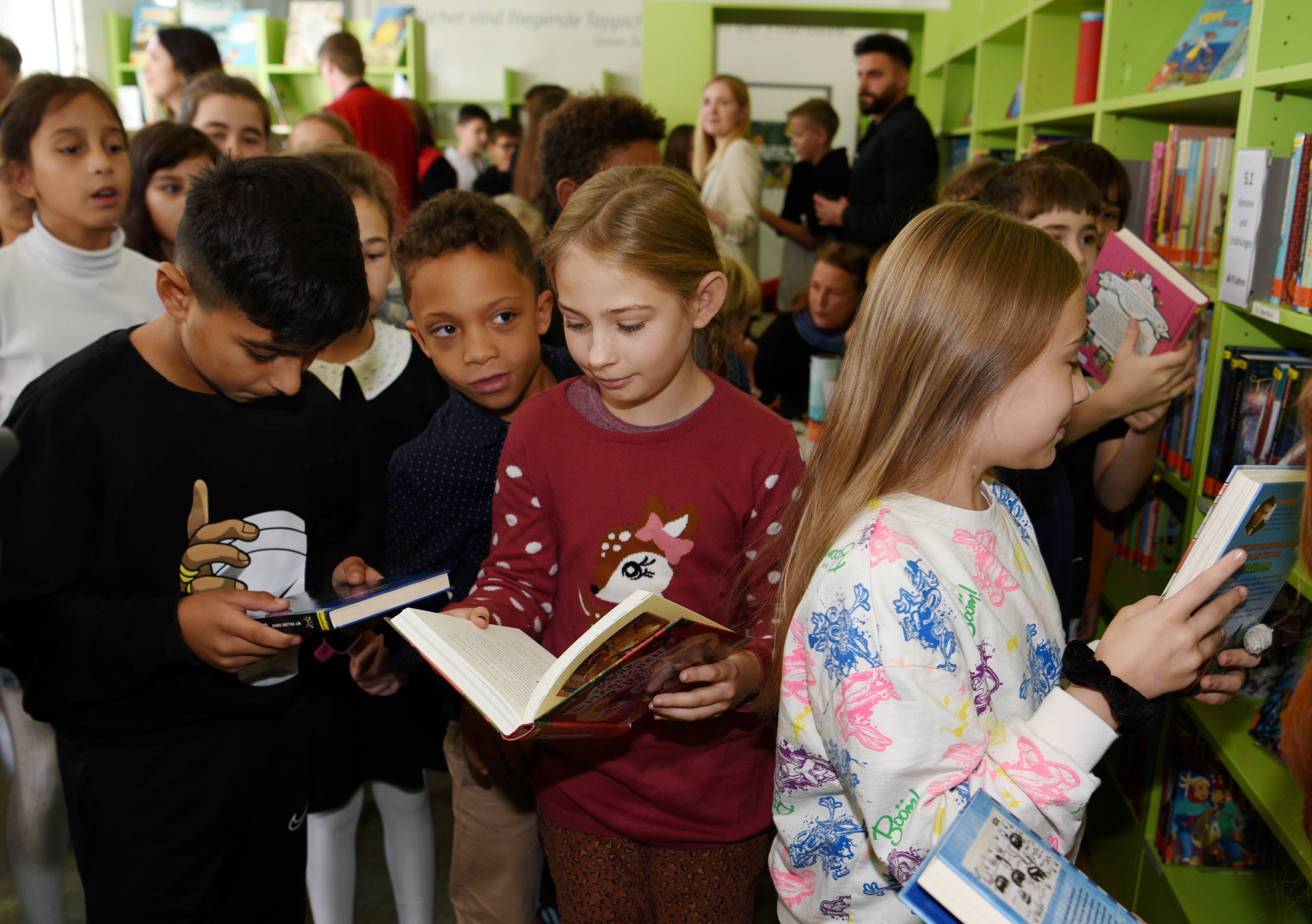 Kinder stehen zusammen und sind in Bücher vertieft