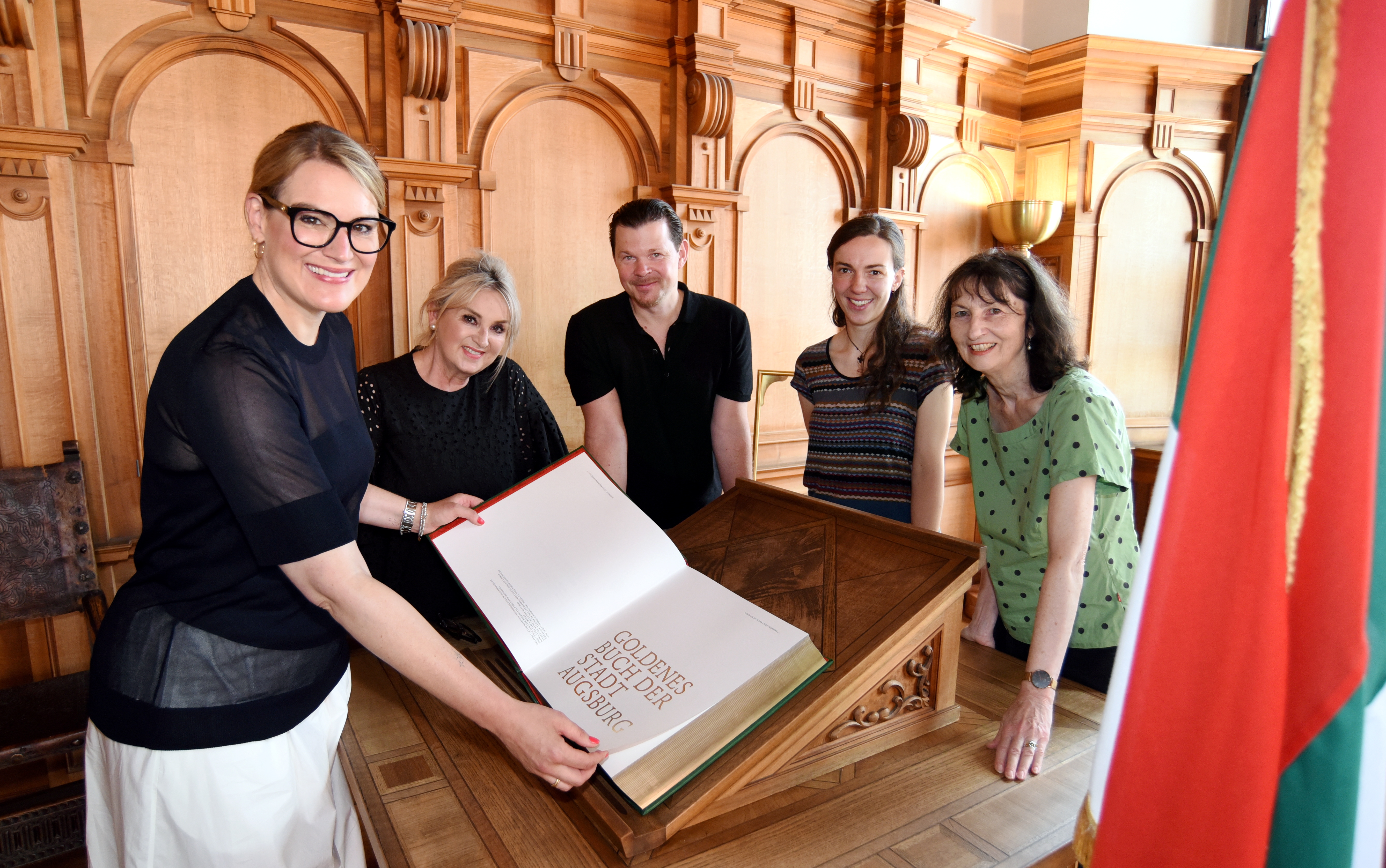 Fünf Menschen stehen um das neue Goldene Buch der Stadt Augsburg
