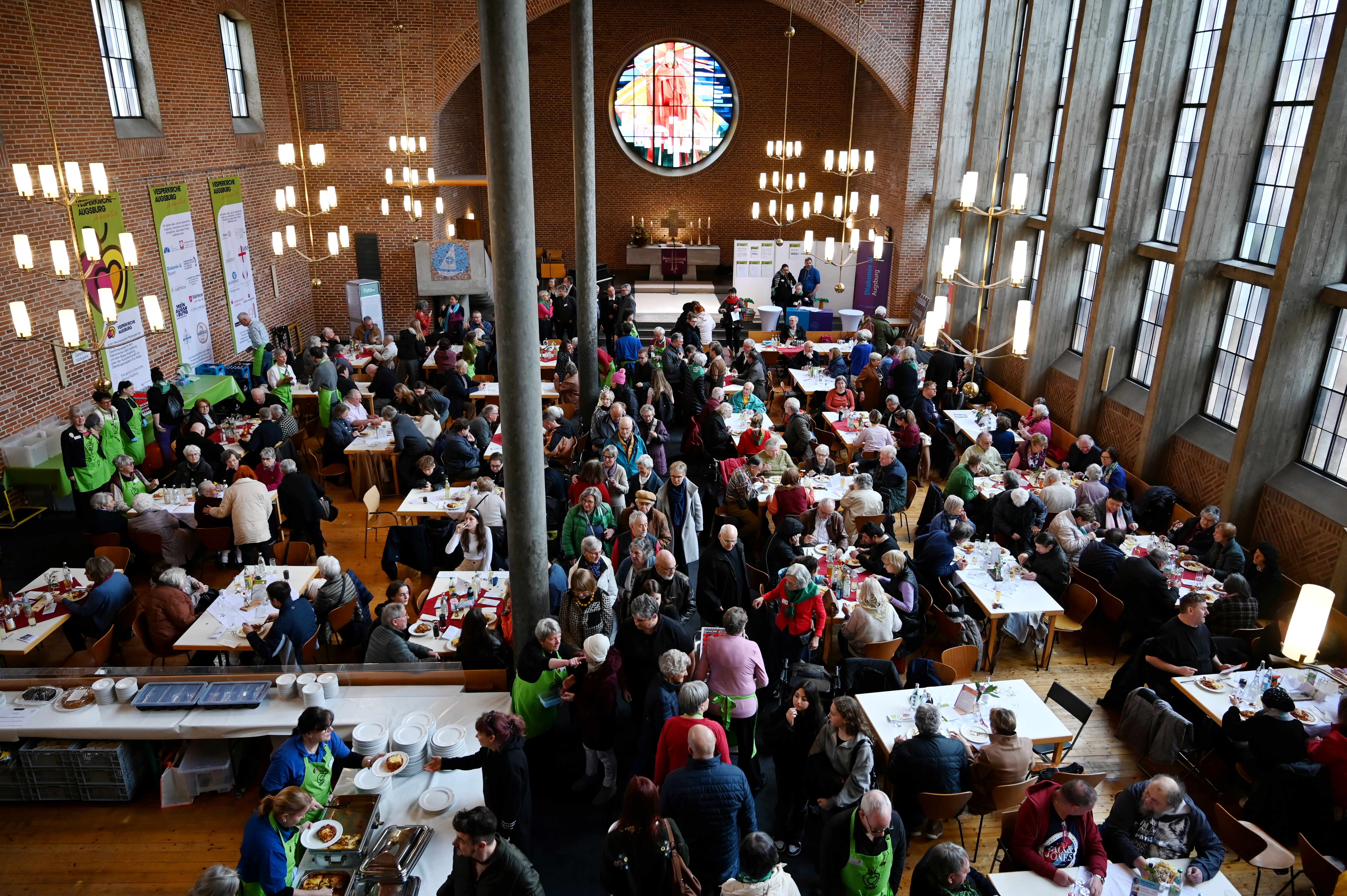 Blick von der Empore auf einen Kirchenraum, der voller Leute ist, die zusammen an Tischen sitzen