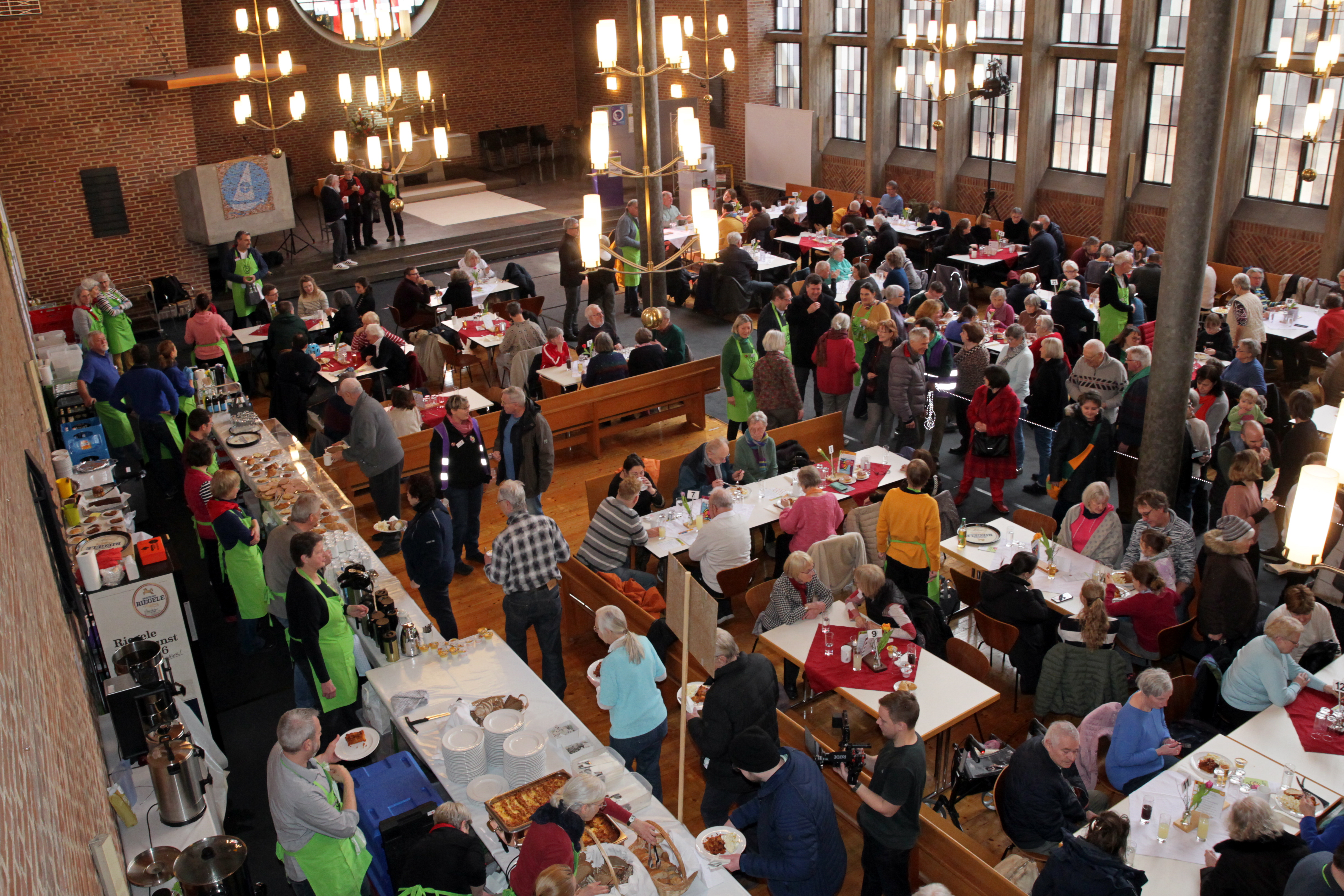 In einer Kirche sind viele Menschen, die an Tischen essen